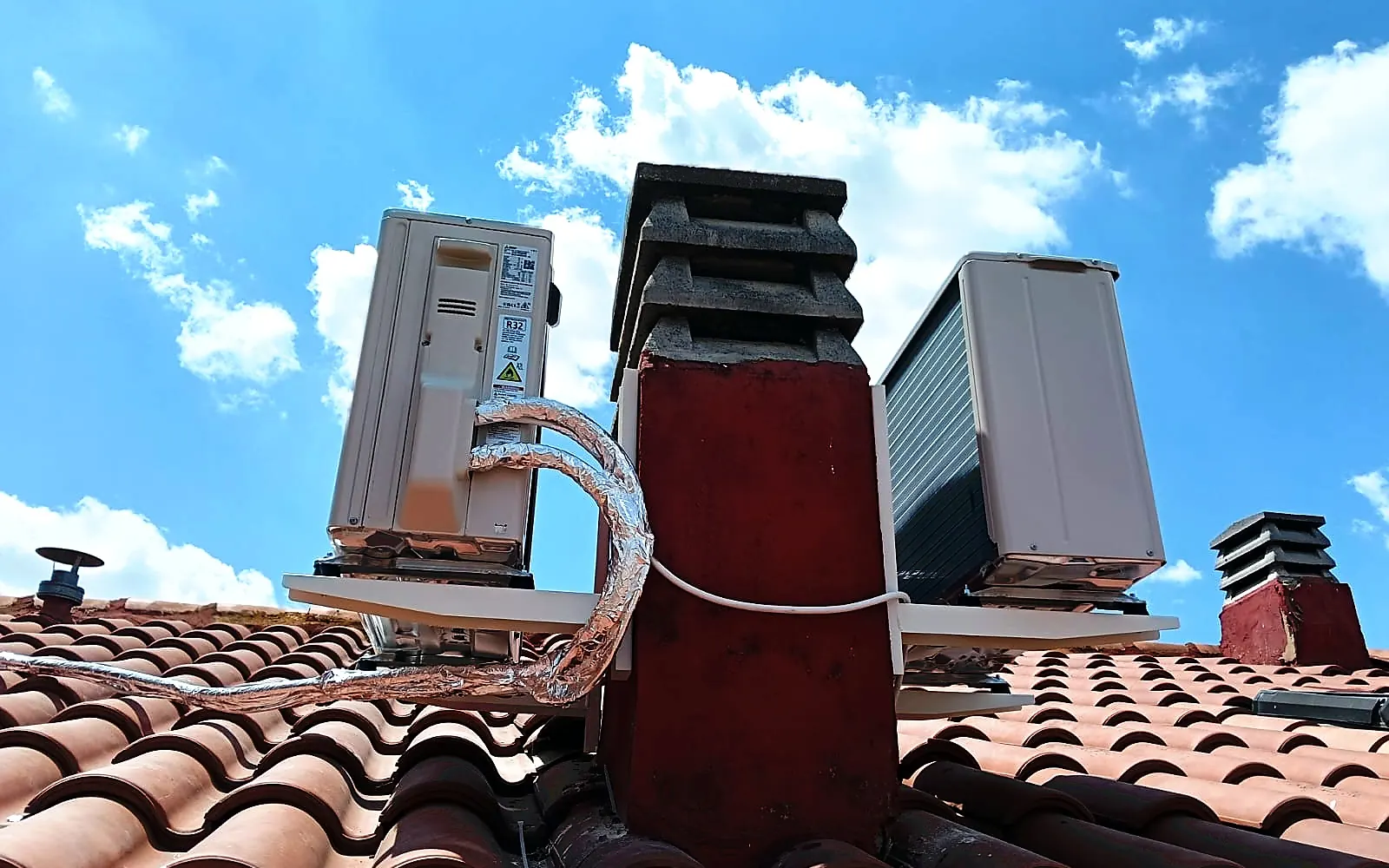 Instalación de aire acondicionado en un tejado: dos unidades exteriores ancladas a chimenea